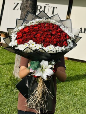 Adana 101 gül ve papatya karışık buket, önü beyaz lilyum süslemeli siyah paketli kız isteme çiçeği.