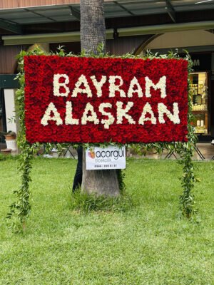 Adana dev gül panosu, kırmızı güllerden çiçek duvarı üzerine beyaz çiçekle isim yazılı lansman dekoru.