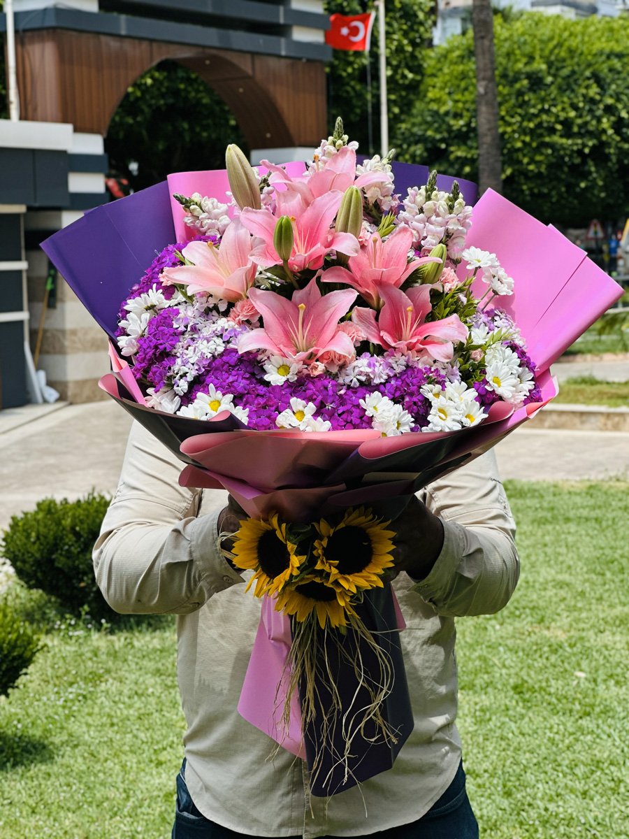 Adana pembe lilyum buketi, etrafı beyaz papatya ve mor çiçeklerle süslü pembe mor ambalajlı tasarım.