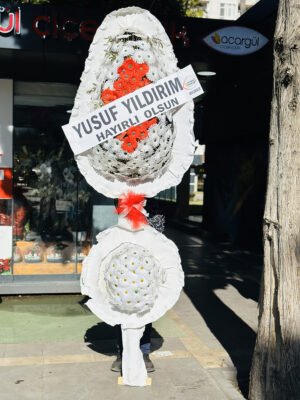 Adana açılış çelengi, beyaz sargılı iskelet üzerine kırmızı ve beyaz çiçeklerle hazırlanmış, ortasında kırmızı tül fiyonk bulunan çift katlı tebrik çelengi.