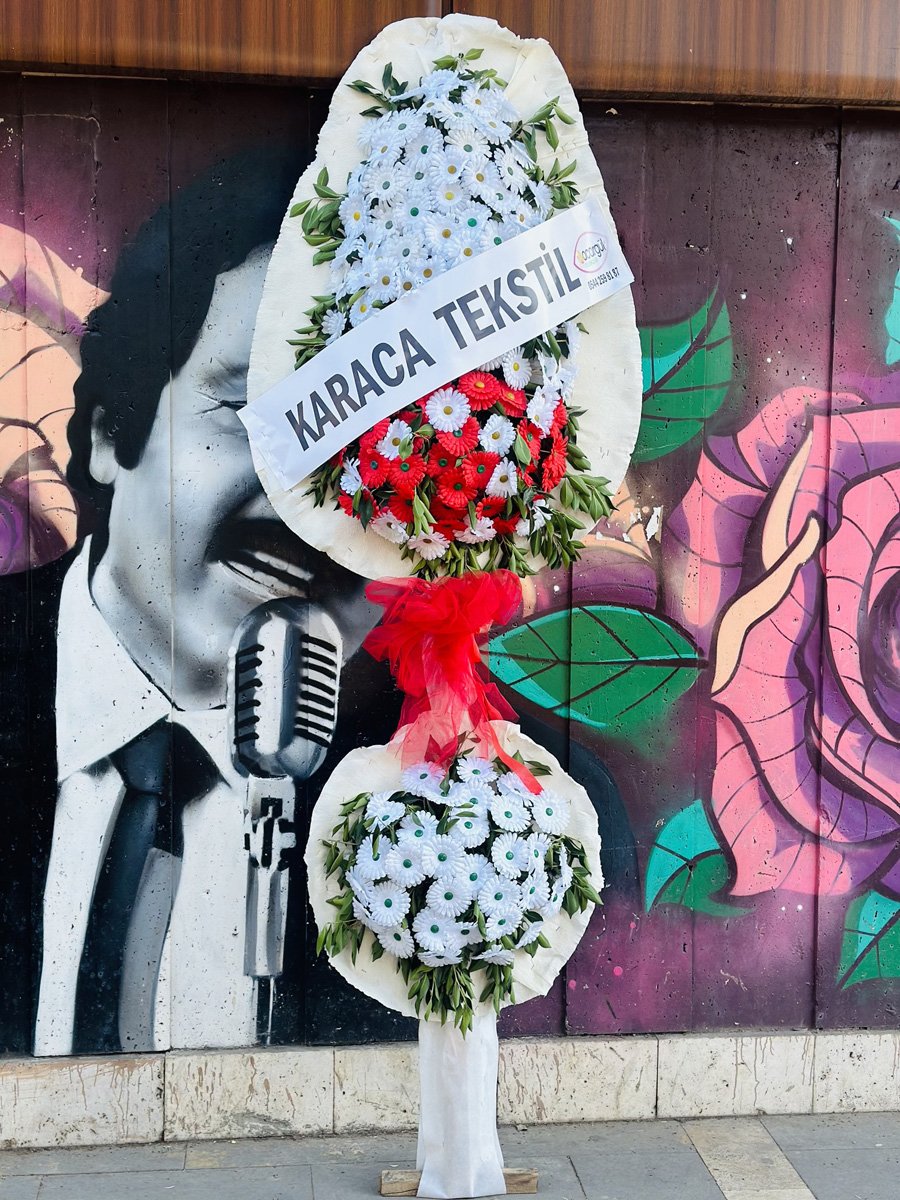 Adana açılış çelengi, beyaz sargılı iskelet üzerine kırmızı ve beyaz çiçeklerle hazırlanmış, ortasında kırmızı tül fiyonk bulunan çift katlı tebrik çelengi.