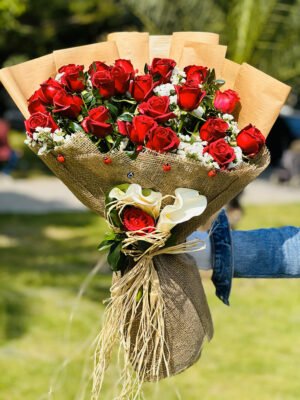 Adana 41 kırmızı gül buketi, rustik çuval bezi ve kraft kağıda sarılı, nazar boncuğu ve uğur böcekleriyle süslenmiş, sapında beyaz gala zambakları bulunan aranjman.