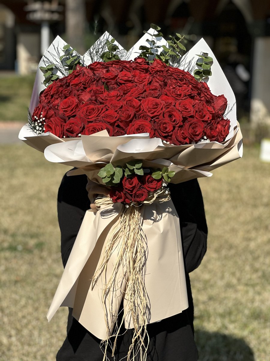 Adana 101 kırmızı gül buketi, latte ve beyaz renkli lüks geometrik kağıda sarılı, okaliptüs ve rafya detaylı dev aranjman.