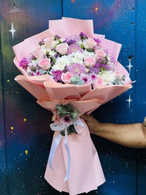 Adana aşk buketi, lüks pembe kağıda sarılı, taze pembe güller, beyaz ve mor krizantemlerle hazırlanan pastel tonlu hacimli aranjman.