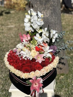 Adana dev kalp kutu aranjmanı, lüks siyah kutuda krem güllerle çerçevelenmiş kırmızı güller, beyaz orkide dalları, renkli lilyumlar ve peluş ayıcık.
