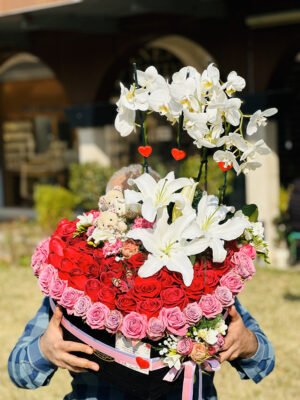 Adana dev kalp kutu aranjmanı, lüks siyah kutuda pembe güllerle çerçevelenmiş kırmızı güller, beyaz lilyum, orkide dalları ve peluş ayıcıklar.