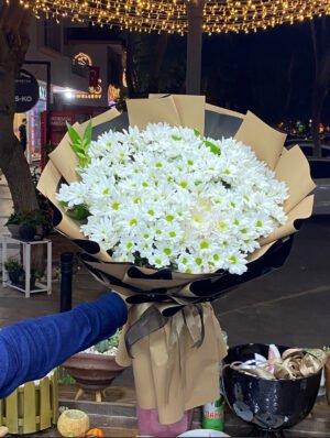 Adana dev papatya buketi, siyah ve kraft renkli çift katmanlı premium ambalaja sarılı kucak dolusu taze beyaz papatya aranjmanı.