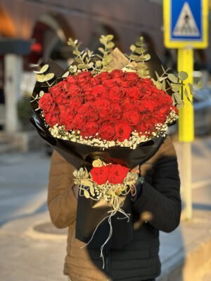 Adana 51 kırmızı gül buketi, lüks siyah kağıda sarılı, aralarında okaliptüs dalları ve etrafında cipso çiçekleri bulunan dev gül aranjmanı.